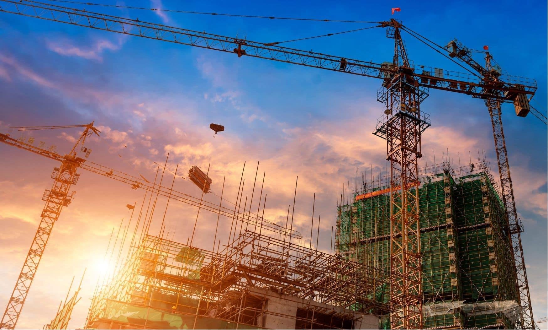 Construction site cranes at sunset