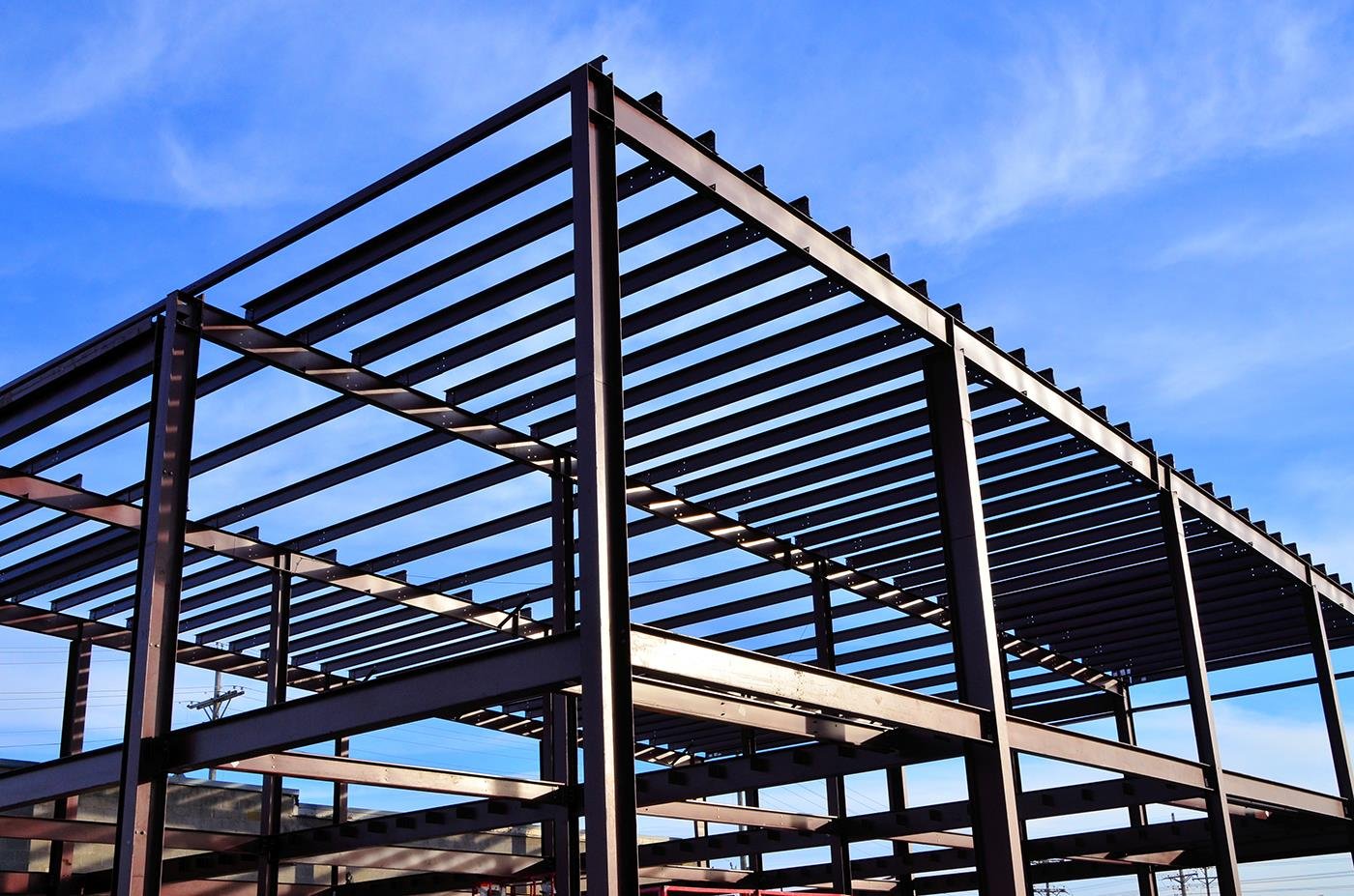 Steel structural frame under construction against a clear blue sky