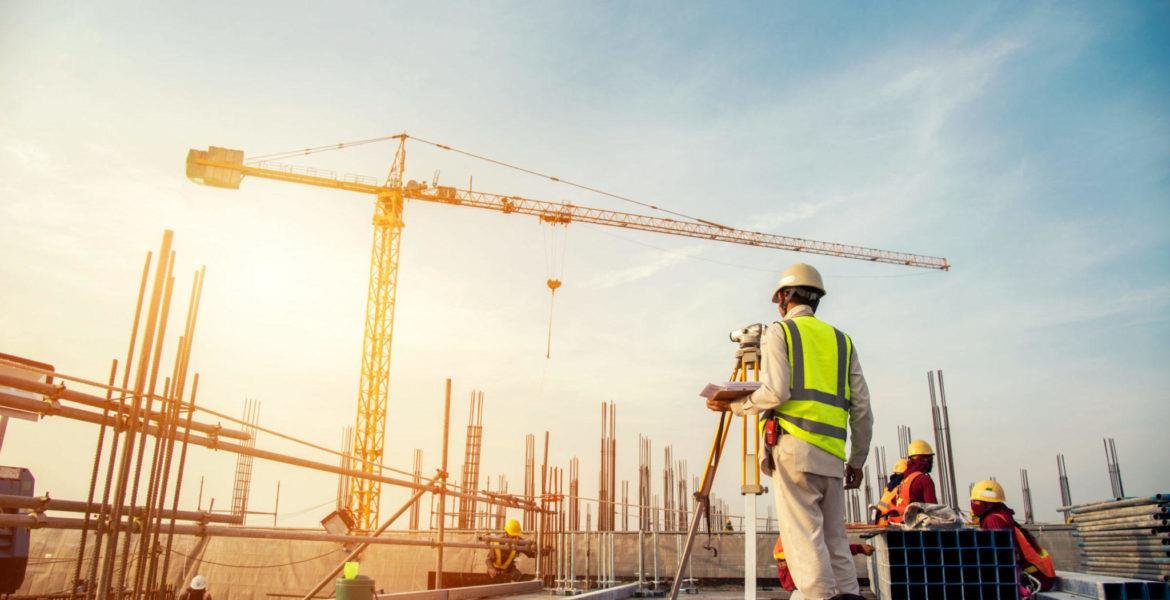 Construction worker on site with crane in background